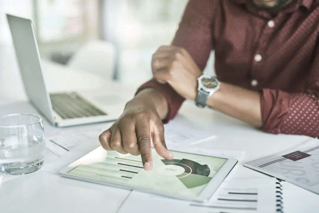 A man sitting at a desk in front of a computer manipulating data on a tablet.