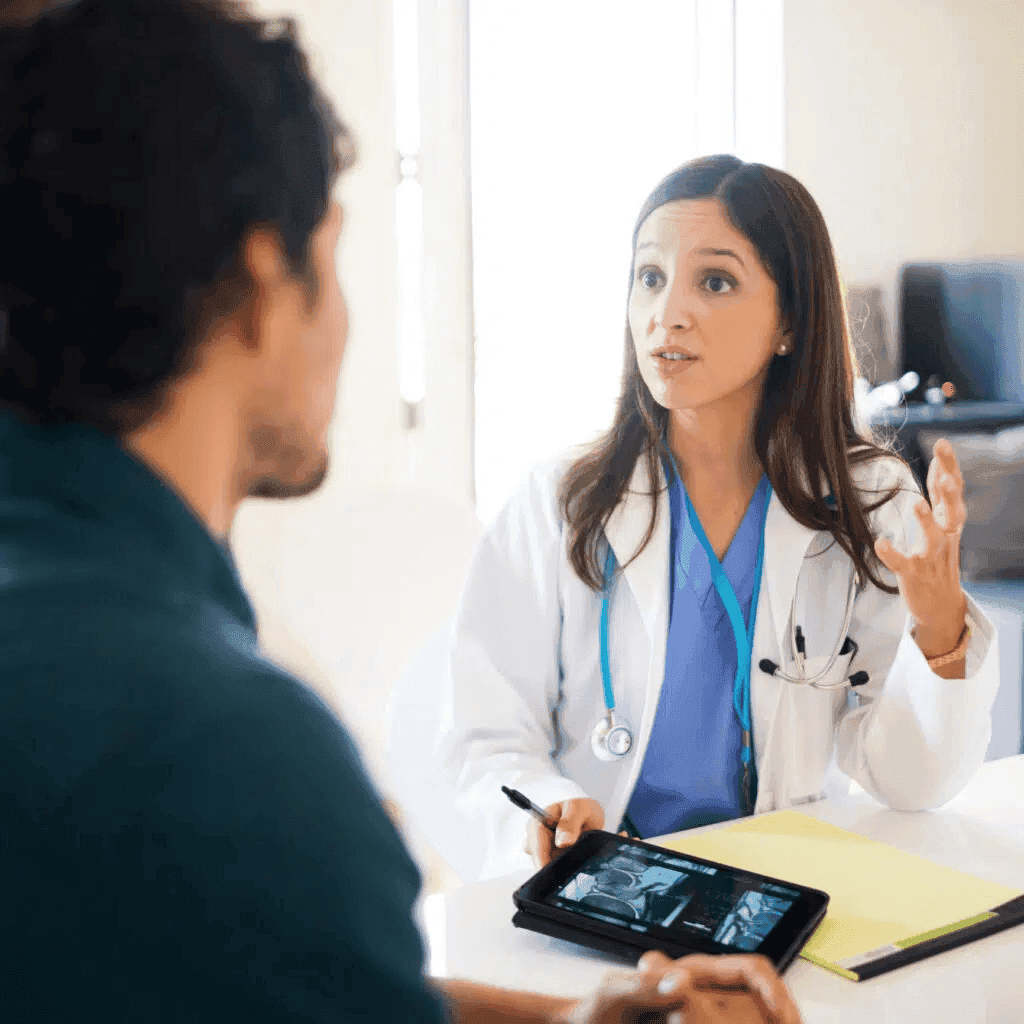 A healthcare provider speaking to a patient and showing him something on a tablet.