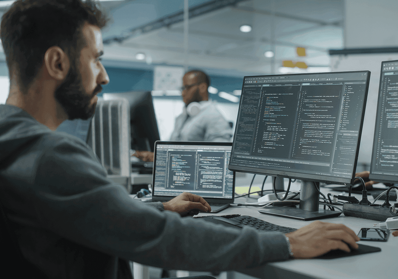A man sitting in front of a computer with multiple screens.