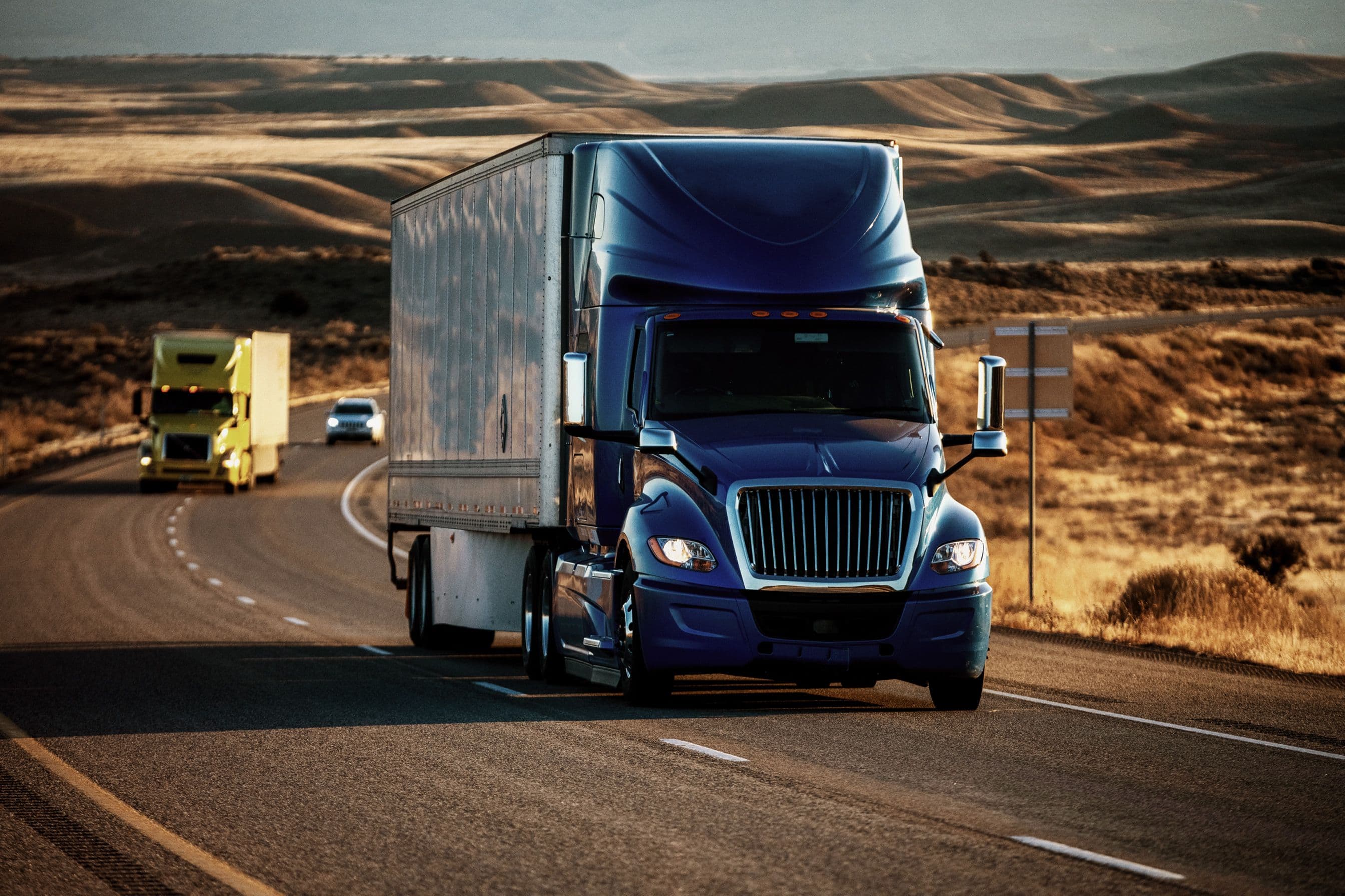 A blue semi truck driving through the desert.